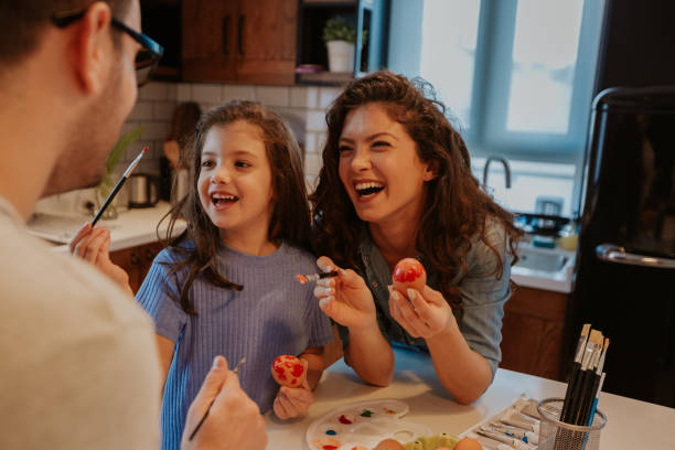 lose up image of lovely brunette and little girl, enjoying easter preparations. Looking at dad, laughing. stock photo