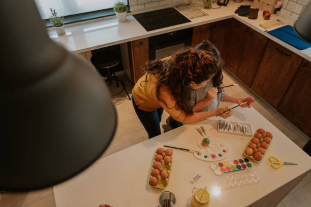 istock High angle image of kitchen table. Mother and child preparing easter eggs for the holiday. Eggs, colors and brushes on the table. 1136011298