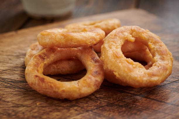 istock stack of onion rings on a rustic wooden chopping board. 1136011704