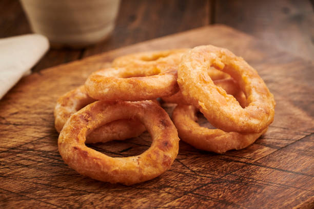 istock stack of onion rings on a rustic wooden chopping board. 1136011708