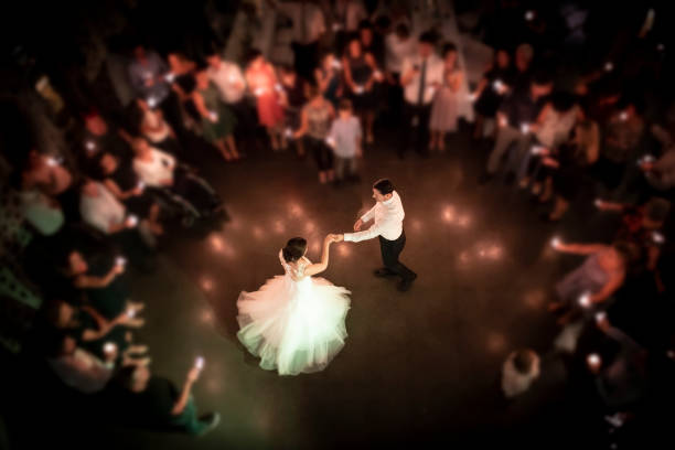 Top view on a wedding couple dancing the opening waltz at their wedding celebration. All their friends are standing in a ring around them with a light in their hands. Focus only on the bridal couple.