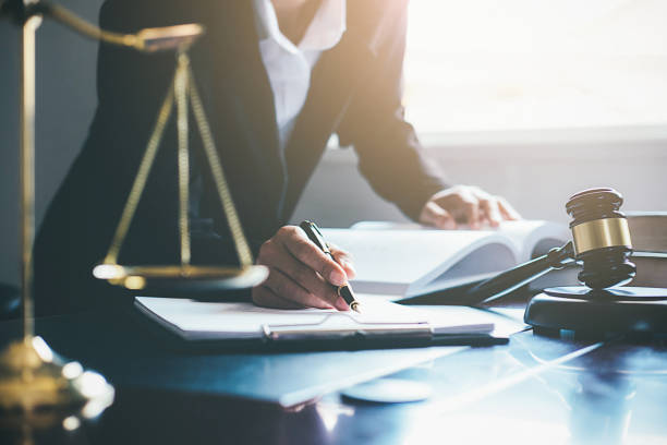 justice and law concept. legal counsel presents to the client a signed contract with gavel and legal law or legal having team meeting at law firm in background - lei imagens e fotografias de stock