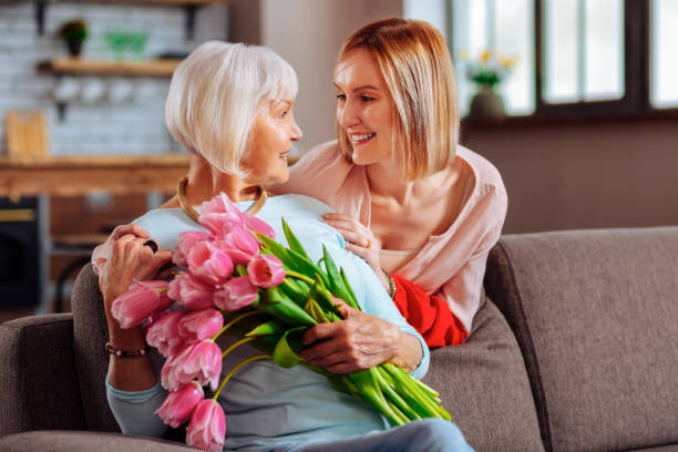 istock Attractive daughter tenderly looking at elderly d smiling mother 1136021181