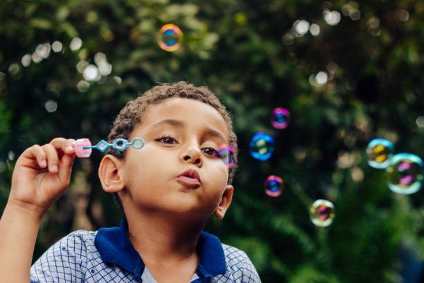 niño jugando burbujas de jabón - bubble wand bubble child playful fotografías e imágenes de stock