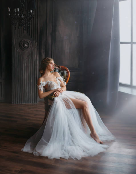 majestic and proud princess girl in white chic oriental white silver dress tired sitting on chair, lady shows off her slender leg and waiting for prince, gentle stylish image of graduate 2019 majestic and proud princess girl in white chic oriental white silver dress tired sitting on chair, lady shows off her slender leg and waiting for prince, gentle stylish image of graduate 2019. swan photos stock pictures, royalty-free photos & images