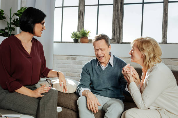 istock Grey-haired man crying during session while his wife crossing her fingers 1136029613
