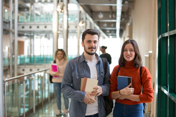 istock Portrait of smiling university students standing in corridor during break 1136030401