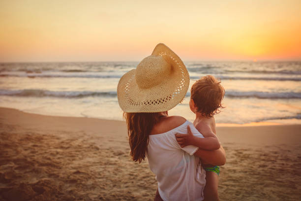 istock Mother with son enjoying sunset on the beach 1136033092