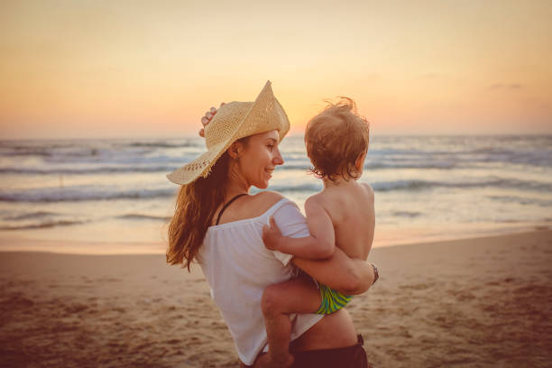 istock Mother with son enjoying sunset on the beach 1136033096
