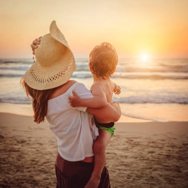 istock Mother with son enjoying sunset on the beach 1136033101