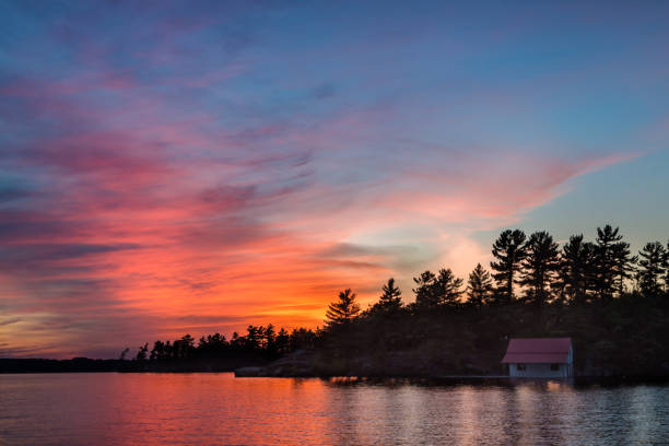 istock Small cottage in shadow on a lake at sunset. 1136035388