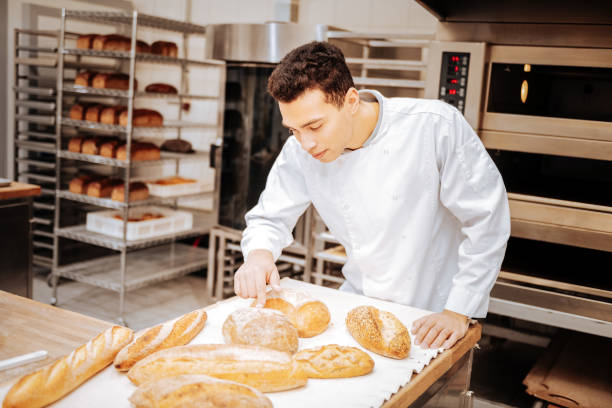 istock Dark-haired baker touching the loaf of bread after baking the tray 1136038075