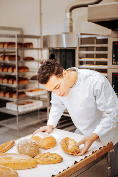 istock Baker looking at the tray and checking the readiness of bread 1136038082