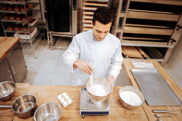 istock Baker beating whites and putting bowl on kitchen scales 1136038169