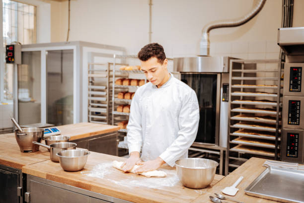 istock Baker working in modern kitchen kneading dough for croissants 1136038189