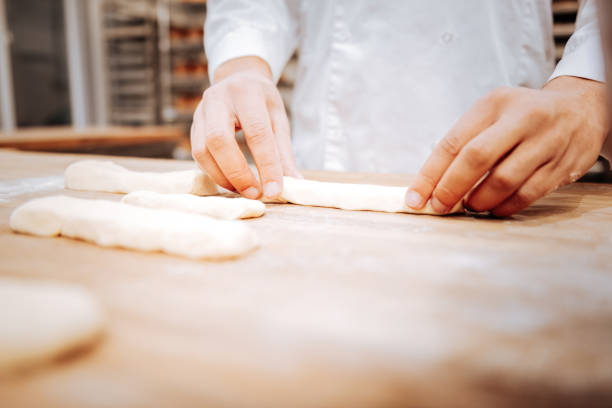 istock Baker standing near the table and putting little formed eclairs on tray 1136038191