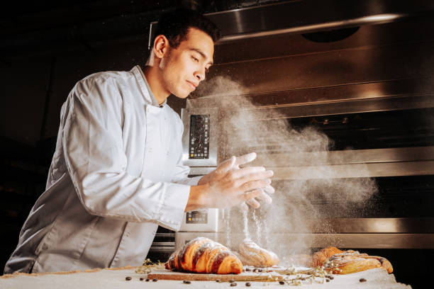 istock Baker in white jacket decorating croissants with sugar powder 1136040071