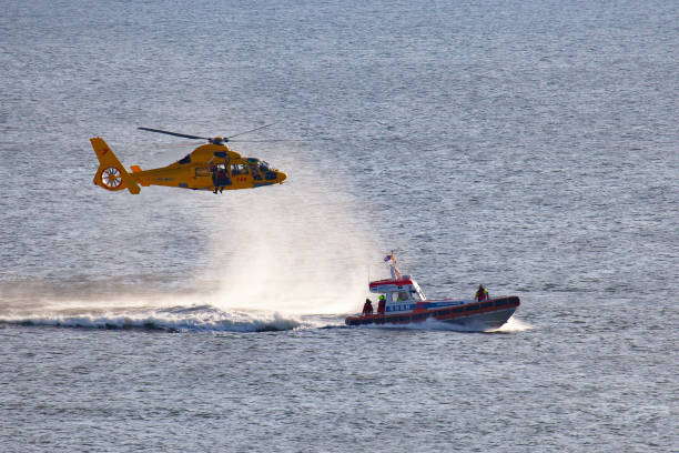 ein hubschrauber nimmt einen mann über dem meer ab - rescue helicopter coast guard protection stock-fotos und bilder