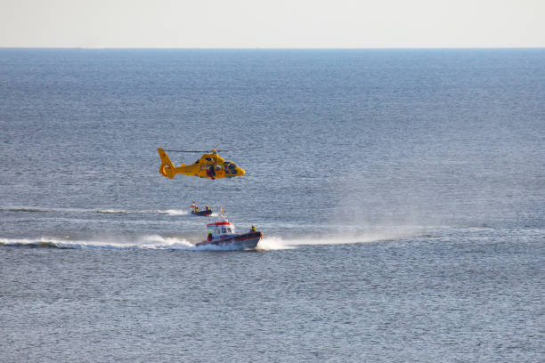 un helicóptero está rappel a un hombre sobre el mar - rescue helicopter coast guard protection fotografías e imágenes de stock