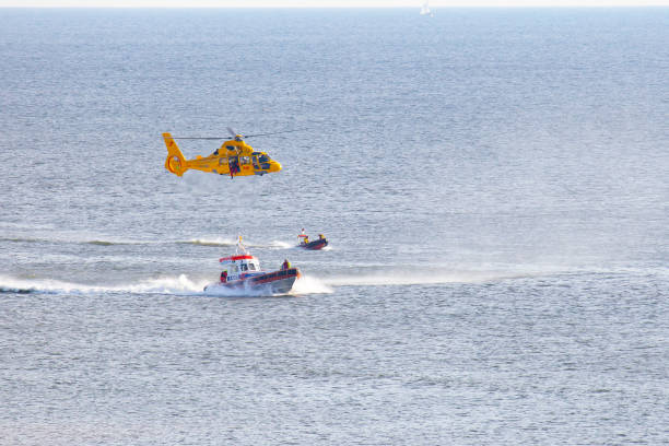 ein hubschrauber nimmt einen mann über dem meer ab - rescue helicopter coast guard protection stock-fotos und bilder