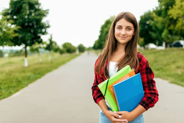 Girl schoolgirl 14-17 years old is in summer in city in a notebook textbooks folders. Free space for text. Happy smiling, resting after school, emotions of joy and fun after classes at institute. chica colegiala 13-16 años de edad es en verano en la ciudad en un cuaderno carpetas de libros de texto. espacio libre para el texto. feliz sonrisa, descansando después de la escuela, emociones de alegría y diversión después de clases en instituto.