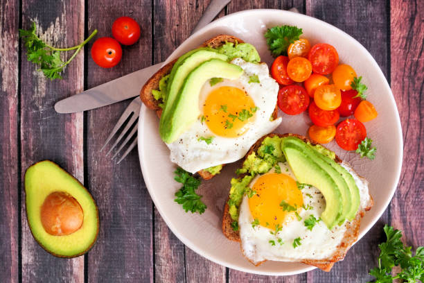 istock Avocado toasts with eggs and tomatoes, above view on dark wood 1136049132