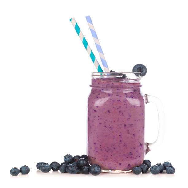 heidelbeer-smoothie in einem maurergefäß mit verstreuten früchten isoliert auf weiß - blueberry smoothie glass striped stock-fotos und bilder