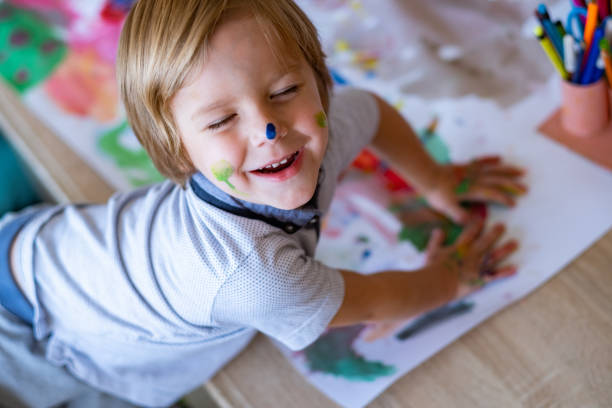 istock cute little boy is doing finger painting 1136050556