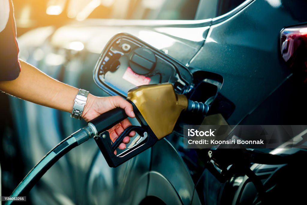 Hand refilling the car with fuel at the refuel station Hand refilling the car with fuel at the refuel station, the concept of fuel energy Gasoline Stock Photo