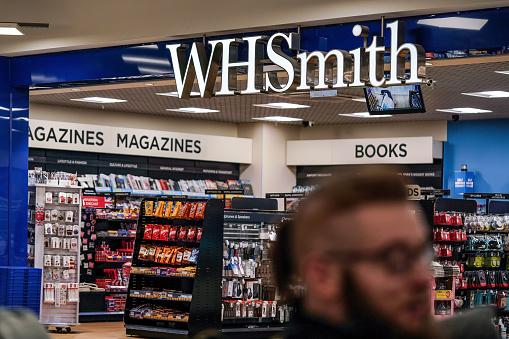 London, United Kingdom - February 05, 2019: Unknown man walks in front of WHSmith branch at London Luton airport. WHS is major British retailer selling mostly books, stationery, magazines newspapers.