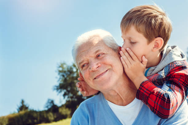 el abuelo y el nieto juntos al aire libre concepto familiar - whispering grandparent child grandfather fotografías e imágenes de stock