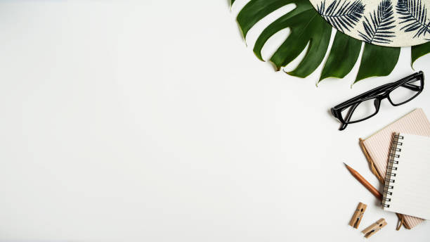 istock Flat lay, top view workspace with eye glasses, notebook, hat, pencil, green leaf, shoes and coffee cup on white background. Summer stylish traveller blogger concept. 1136057312