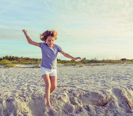 Little girl in shorts runs along a idyllic stretch of beach in paradise. Cayo Costa State Park in Florida, stunning, deserted and full of natural splendor, a child in nature, happy, active, and with enthusiasm