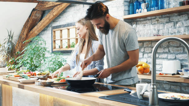 istock Young couple making dinner together at home 1136060686