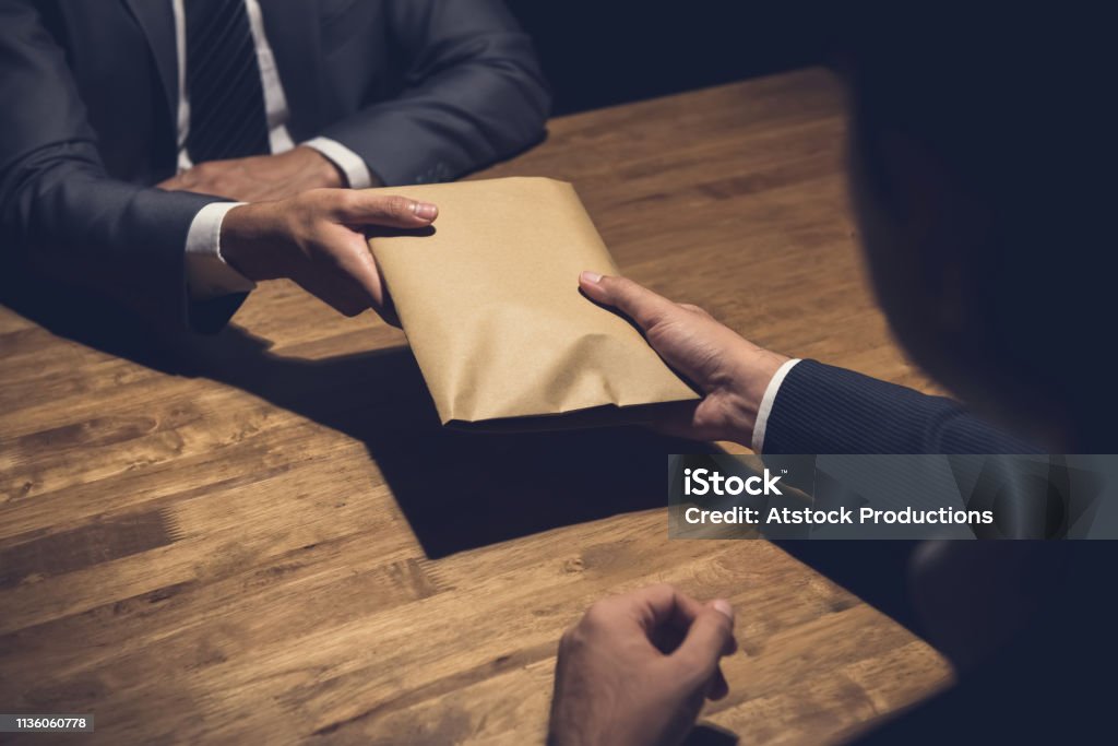 Businessman giving money in the envelope to his partner in the dark Businessman giving money in the envelope to his partner in the dark - bribery and venality concept Bribing Stock Photo