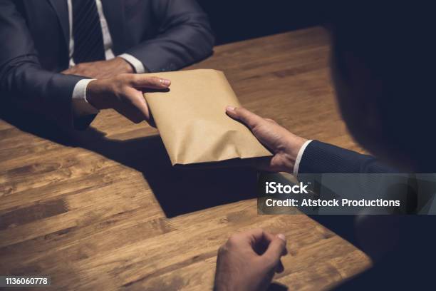 Businessman Giving Money In The Envelope To His Partner In The Dark Stock Photo - Download Image Now