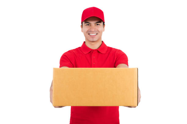 istock Smiling delivery man in red uniform giving a box, isolated on white background 1136060784