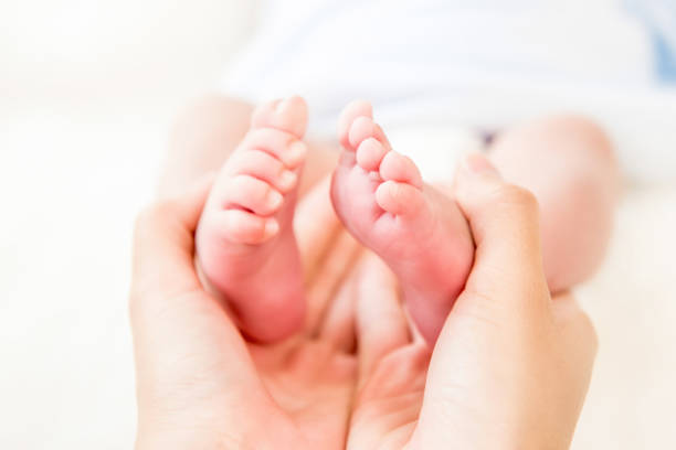 istock Mother hands gently holding small baby feet 1136060801