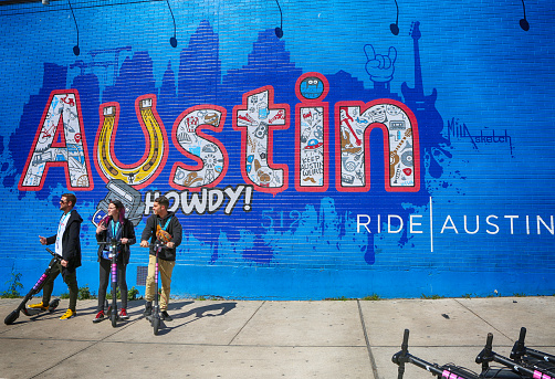 Austin, Texas, March 14, 2019, SXSW South by Southwest Annual music, film, and interactive conference and festival. Members of SXSW in front of wall painting at 6th street, using electric scooter-popular transportation in city.