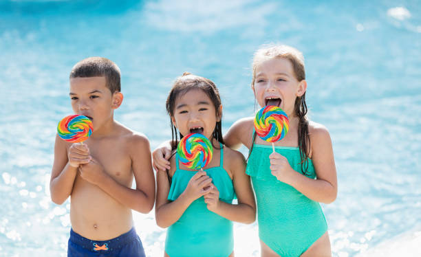 crianças multi-étnicas na piscina com pirulitos - embracing smiling gap children only - fotografias e filmes do acervo