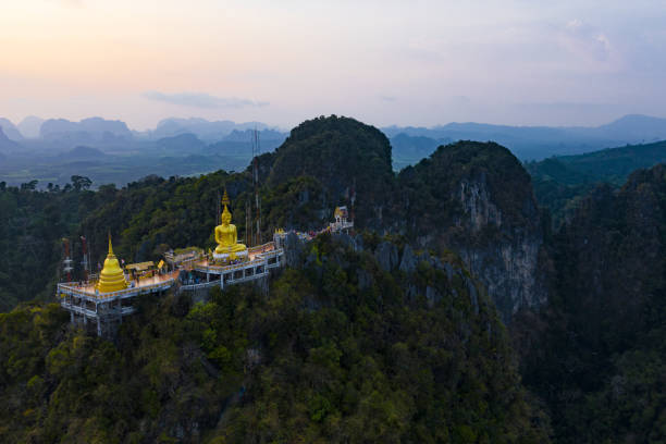 View from above, stunning aerial view of the beautiful Tiger Cave Temple (Wat Tham Sua) surrounded by amazing ridges of limestone mountains during the sunset. Krabi, Thailand. View from above, stunning aerial view of the beautiful Tiger Cave Temple (Wat Tham Sua) surrounded by amazing ridges of limestone mountains during the sunset. Krabi, Thailand. wat tham sua stock pictures, royalty-free photos & images