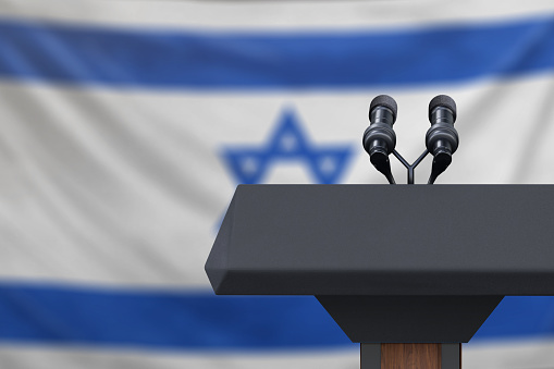 Podium lectern with two microphones and Israel flag in background