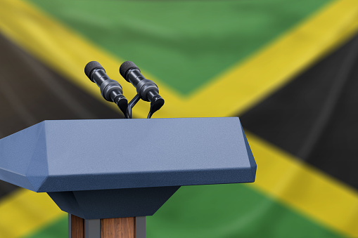 Podium lectern with two microphones and Jamaica flag in background