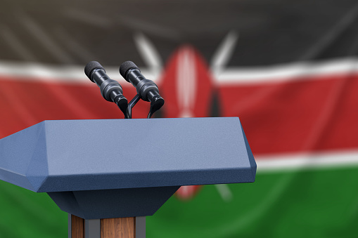 Podium lectern with two microphones and Kenya flag in background