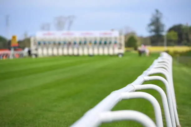 Racecourse in the early afternoon looking at the safety barriers with starting gates in the background