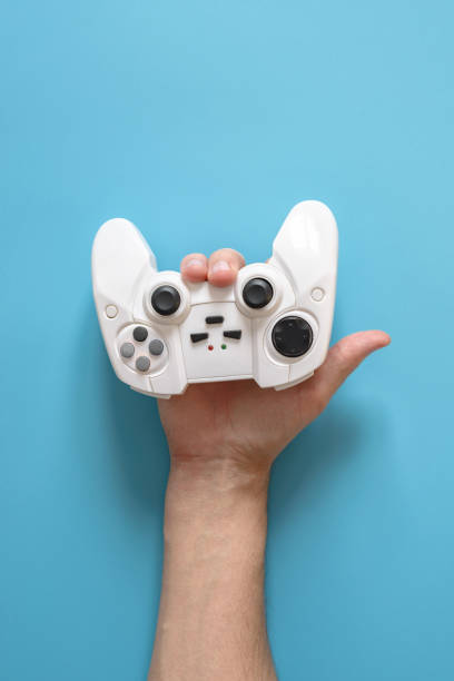 istock A man's hand holds a white joystick console like sign of the horns. Blue solid background. 1136092615