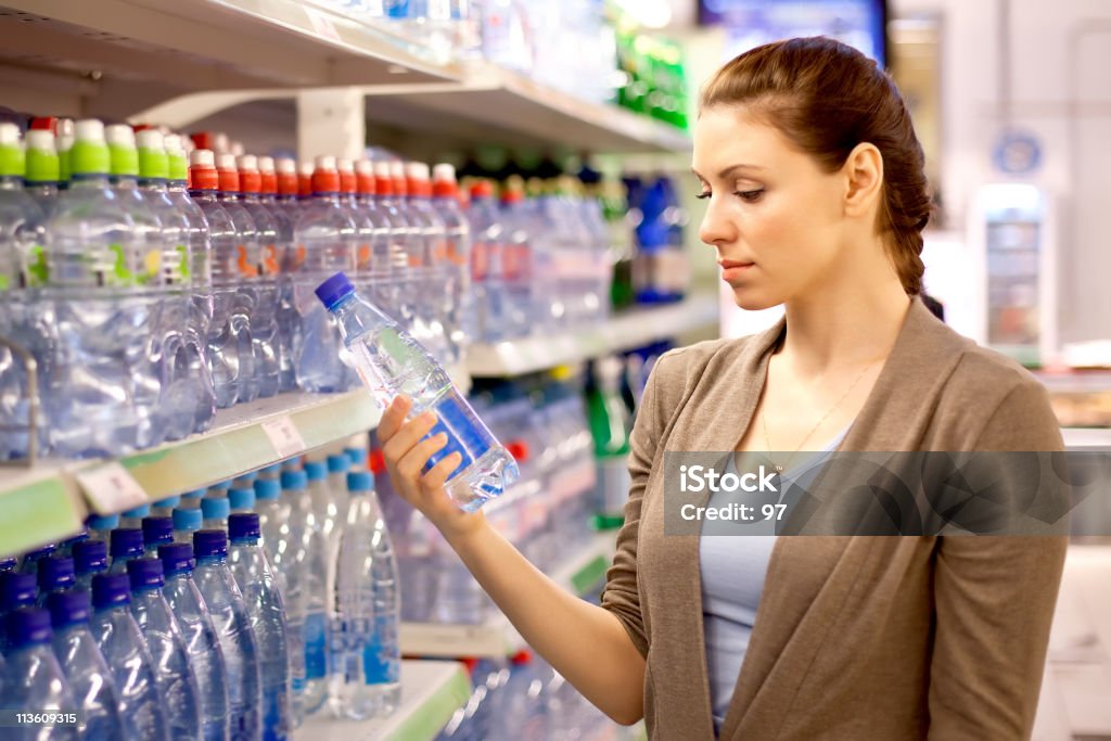 a mulher compra uma garrafa de água na loja - Royalty-free Supermercado Foto de stock