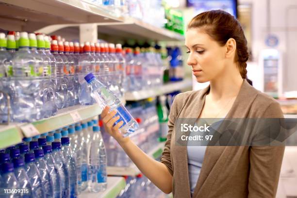 A Mulher Compra Uma Garrafa De Água Na Loja - Fotografias de stock e mais imagens de Supermercado - Supermercado, Garrafa de água - Garrafa, Fazer Compras
