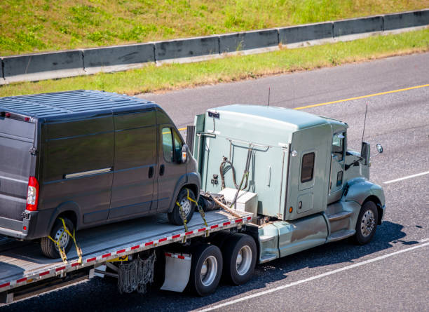 istock Powerful big rig classic semi truck transporting mini van fastened on flat bed semi trailer running on wide highway 1136099491