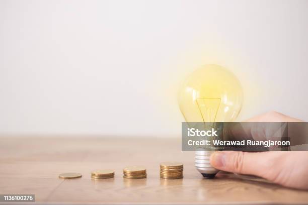 New Idea Concept With Coins Stack Young Women Hand Holding Light Bulb With New Knowledge On Wooden Backgrounds And New Idea Concept Save Power To Save The Earth Stock Photo - Download Image Now